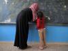 在北拉卡市的Hazema，一名女孩在上她的第一堂课。破烂的黑板，教师黑色长袍，女孩红色外衣对比是那么明显，背影是那么震撼。